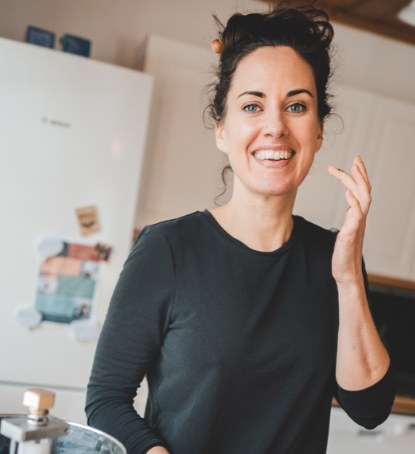 Sara Johansson i köket, leende med chokladspatel.